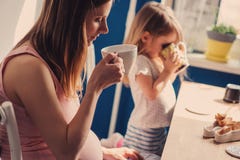 Pregnant Woman With Her Toddler Daughter Drinking Tea For Breakfast At Home Royalty Free Stock Photos