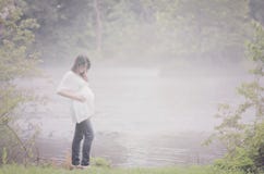 Pregnant woman by foggy river