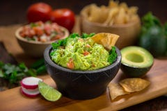 Premium handmade Guacamole from fresh organic avocados with chips on a table with pico de gallo salsa stock images Premium handmade Guacamole from fresh organic avocados with chips on a table with pico de gallo salsa stock images