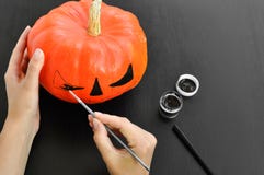 Preparation for Halloween: women`s hands paint orange pumpkin with black paint. Closup. Holiday decoration concept. royalty free stock photos Preparation for Halloween: women`s hands paint orange pumpkin with black paint. Closup. Holiday decoration concept. royalty free stock photos
