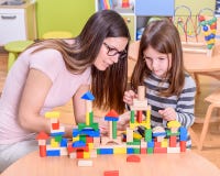 Preschool Teacher Instructs Cute Girl how to Build Toy Castle stock photo Preschool Teacher Instructs Cute Girl how to Build Toy Castle stock photo
