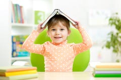 Preschooler dzieciaka dziewczyna z książką nad jej głową zdjęcia stock Preschooler dzieciaka dziewczyna z książką nad jej głową zdjęcia stock