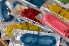 Preservativos coloridos em uns pacotes da folha de modo operacional foto de stock Preservativos coloridos em uns pacotes da folha de modo operacional foto de stock