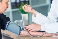 Pressione sanguigna di misurazione del cardiologo di medico del paziente femminile immagine stock libera da diritti Pressione sanguigna di misurazione del cardiologo di medico del paziente femminile immagine stock libera da diritti