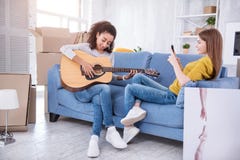 Prettige jonge de kamergenoot van de meisjesopname het spelen gitaar royalty-vrije stock afbeelding Prettige jonge de kamergenoot van de meisjesopname het spelen gitaar royalty-vrije stock afbeelding