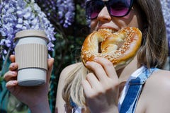 Pretty blonde woman holding cup of coffee and sweet pretzel in a stock photos Pretty blonde woman holding cup of coffee and sweet pretzel in a stock photos