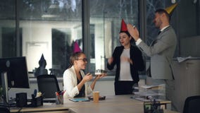 Pretty blonde is working in modern office when her colleagues are bringing birthday cake, present and party hats, girl stock footage Pretty blonde is working in modern office when her colleagues are bringing birthday cake, present and party hats, girl stock footage