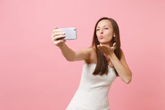 Pretty bride woman in white wedding dress blowing lips, sending air kiss, doing taking selfie shot on mobile phone