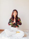 A pretty Chinese young woman practicing yoga at home, sitting on floor with furry cushion near sunny glass door, exercise stock image A pretty Chinese young woman practicing yoga at home, sitting on floor with furry cushion near sunny glass door, exercise stock image