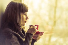 Pretty Girl Drinking Coffee Or Tea Near Window. Warm Colors Toned Royalty Free Stock Photography