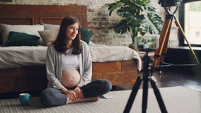 Pregnant woman female blogger is recording video for followers about pregnancy, girl is sitting on bedroom floor stock video Pregnant woman female blogger is recording video for followers about pregnancy, girl is sitting on bedroom floor stock video