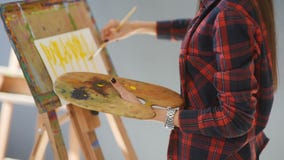 Pretty Pretty Girl artist paints on canvas painting on the easel. Studio black background. Long hair, brunette stock video footage Pretty Pretty Girl artist paints on canvas painting on the easel. Studio black background. Long hair, brunette stock video footage