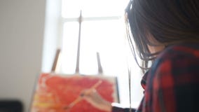 Pretty Pretty Girl artist paints on canvas painting on the easel. Studio black background. Long hair, brunette stock video Pretty Pretty Girl artist paints on canvas painting on the easel. Studio black background. Long hair, brunette stock video