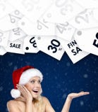Pretty woman in Christmas cap gestures palm up special prices royalty free stock photography Pretty woman in Christmas cap gestures palm up special prices royalty free stock photography