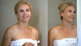 Pretty woman holding toothbrush with toothpaste looking at camera and smiling stock photo Pretty woman holding toothbrush with toothpaste looking at camera and smiling stock photo