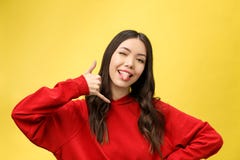 Pretty young woman showing phone sign with her fingers. Colorful studio portrait with yellow background. royalty free stock photos Pretty young woman showing phone sign with her fingers. Colorful studio portrait with yellow background. royalty free stock photos