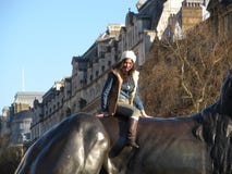 Fashionable Young Woman Poses Atop Bronze Lion, London, England, UK