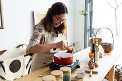 Pretty young woman spicing up the food while cooking in an organic store. Stock Photos Pretty young woman spicing up the food while cooking in an organic store. Stock Photos