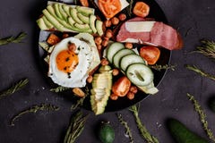 Prima colazione casalinga con il pomodoro affettato, bacon, pani, cetriolo, uovo, avocado, nocciola sul piatto fotografia stock Prima colazione casalinga con il pomodoro affettato, bacon, pani, cetriolo, uovo, avocado, nocciola sul piatto fotografia stock