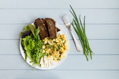 Prima colazione sana: pane tostato grano intero, uova rimescolate, insalate Il piano mette sulla tavola di legno grigia fotografia stock libera da diritti Prima colazione sana: pane tostato grano intero, uova rimescolate, insalate Il piano mette sulla tavola di legno grigia fotografia stock libera da diritti