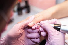 Primer de la manicura del hardware en un salón de belleza Manicure el proceso, limpieza de clavos por una fresa imagen de archivo libre de regalías Primer de la manicura del hardware en un salón de belleza Manicure el proceso, limpieza de clavos por una fresa imagen de archivo libre de regalías