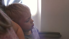 Primer de un niño pequeño que duerme en un aeroplano que se inclina en el hombro de su madre metrajes Primer de un niño pequeño que duerme en un aeroplano que se inclina en el hombro de su madre metrajes
