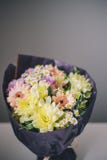 Primer de un ramo de flores coloridas en soportes de empaquetado p?rpuras en una tabla blanca imágenes de archivo libres de regalías Primer de un ramo de flores coloridas en soportes de empaquetado p?rpuras en una tabla blanca imágenes de archivo libres de regalías