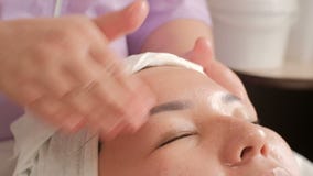 Primer Masaje de cara El cosmetologist profesional alisa la piel de una mujer de mediana edad asiática El movimiento de la cámara almacen de video Primer Masaje de cara El cosmetologist profesional alisa la piel de una mujer de mediana edad asiática El movimiento de la cámara almacen de video