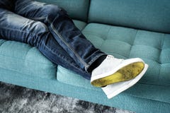 Primo piano delle gambe del ` s della persona che si siedono sullo strato fotografia stock libera da diritti Primo piano delle gambe del ` s della persona che si siedono sullo strato fotografia stock libera da diritti