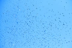 Primo piano delle goccioline di acqua di caduta su fondo blu immagini stock libere da diritti Primo piano delle goccioline di acqua di caduta su fondo blu immagini stock libere da diritti