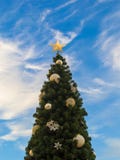 Primo piano di un albero di Natale contro un cielo blu con le nuvole bianche Albero di Natale decorato con una stella d'oro e le fotografia stock Primo piano di un albero di Natale contro un cielo blu con le nuvole bianche Albero di Natale decorato con una stella d'oro e le fotografia stock