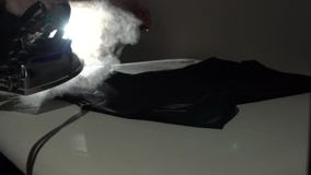 Proceso de la adaptación Camiseta negra que plancha con vapor Cierre de la cámara lenta para arriba almacen de metraje de vídeo Proceso de la adaptación Camiseta negra que plancha con vapor Cierre de la cámara lenta para arriba almacen de metraje de vídeo