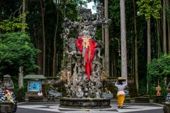 Processione di belle donne di balinese in costumi tradizionali - sarong, andante alla cerimonia indù vicino al grande monumento d fotografia stock Processione di belle donne di balinese in costumi tradizionali - sarong, andante alla cerimonia indù vicino al grande monumento d fotografia stock