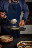 Processo de cozinhar panquecas em um fogão de madeira Um homem derrama a massa da concha na bandeja imagens de stock royalty free Processo de cozinhar panquecas em um fogão de madeira Um homem derrama a massa da concha na bandeja imagens de stock royalty free