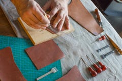 Processus fonctionnant dans l'atelier en cuir Homme tenant ouvrer l'outil et le travail Il coud pour faire un walet Tanner dedans photographie stock Processus fonctionnant dans l'atelier en cuir Homme tenant ouvrer l'outil et le travail Il coud pour faire un walet Tanner dedans photographie stock