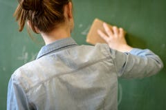 Profesor de sexo femenino o una pizarra de la limpieza del estudiante con una esponja foto de archivo Profesor de sexo femenino o una pizarra de la limpieza del estudiante con una esponja foto de archivo