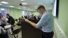 Profesor hermoso en la camisa blanca que se prepara para comenzar la presentación delante de estudiantes en sala de clase metrajes Profesor hermoso en la camisa blanca que se prepara para comenzar la presentación delante de estudiantes en sala de clase metrajes