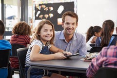 Profesor y colegiala que usa la tableta en mirada de la clase a la cámara foto de archivo libre de regalías Profesor y colegiala que usa la tableta en mirada de la clase a la cámara foto de archivo libre de regalías