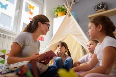Professeur préscolaire lisant une histoire aux enfants au jardin d'enfants photo libre de droits Professeur préscolaire lisant une histoire aux enfants au jardin d'enfants photo libre de droits