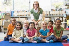 Professeur s'asseyant avec des enfants dans la bibliothèque image libre de droits Professeur s'asseyant avec des enfants dans la bibliothèque image libre de droits