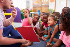 Professeur volontaire lisant à une classe des enfants préscolaires photo libre de droits Professeur volontaire lisant à une classe des enfants préscolaires photo libre de droits