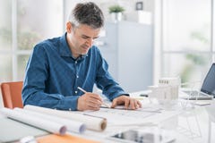 Professional architect working at office desk, he is drawing and making measurements on a project blueprint, engineering and royalty free stock image Professional architect working at office desk, he is drawing and making measurements on a project blueprint, engineering and royalty free stock image