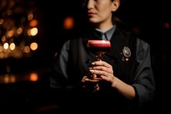 Professional bartender girl serving a smooth crimson cocktail in the glass with a one pink rose bud as a decor stock photography Professional bartender girl serving a smooth crimson cocktail in the glass with a one pink rose bud as a decor stock photography