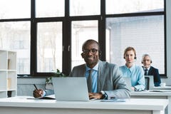 professional multiethnic business people in headsets using laptops and smiling at camera royalty free stock images professional multiethnic business people in headsets using laptops and smiling at camera royalty free stock images