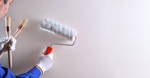 Professional painter with roller on white wall stock photo Professional painter with roller on white wall stock photo