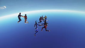 Professional skydivers parachuting above coast of Dubai. Formation. Dance. Sunny