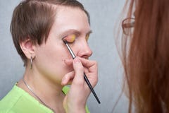 Professional visage artist applying color makeup on woman`s face on grey background. stock photo Professional visage artist applying color makeup on woman`s face on grey background. stock photo