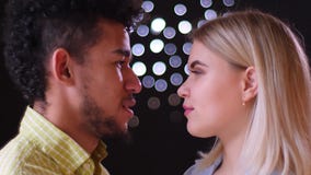 Profile portrait of multinational couple watching passionately and smilingly into eyes on blurred lights background. stock video Profile portrait of multinational couple watching passionately and smilingly into eyes on blurred lights background. stock video