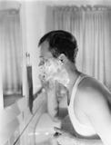 Profile of a young man in front of a mirror in a bathroom shaving royalty free stock photo Profile of a young man in front of a mirror in a bathroom shaving royalty free stock photo