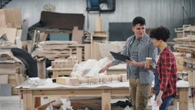 Propietarios de negocio que hablan en el taller de madera que sostiene el café, los papeles y la tableta metrajes Propietarios de negocio que hablan en el taller de madera que sostiene el café, los papeles y la tableta metrajes
